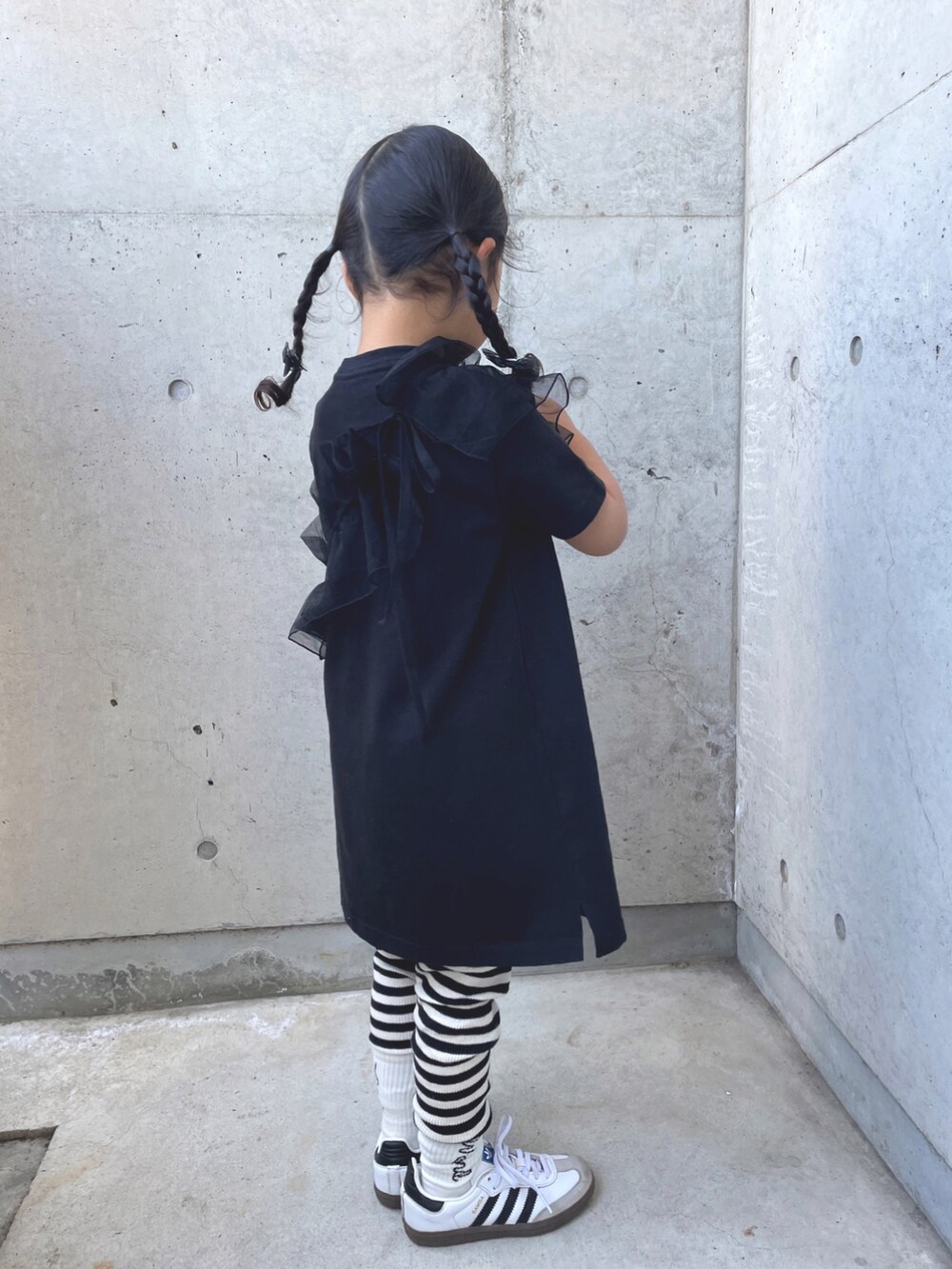 ブラック系のワンピース、ホワイト系のスニーカー、ブラック系のバレッタ/ヘアクリップを着用したキッズの春コーディネートの5枚目の写真