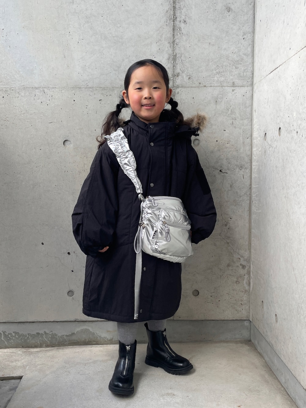 シルバー系のショルダーバッグ、ブラック系のミリタリージャケット、ブラック系のブーツを着用したキッズの冬コーディネートの4枚目の写真