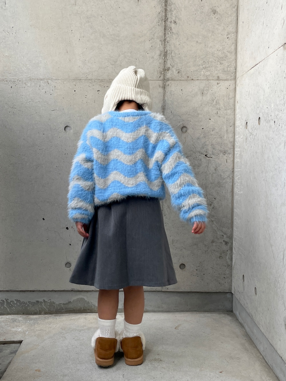 グレー系のスーツセット、ブルー系のニット/セーター、ブラウン系のブーツを着用したキッズの冬コーディネートの2枚目の写真