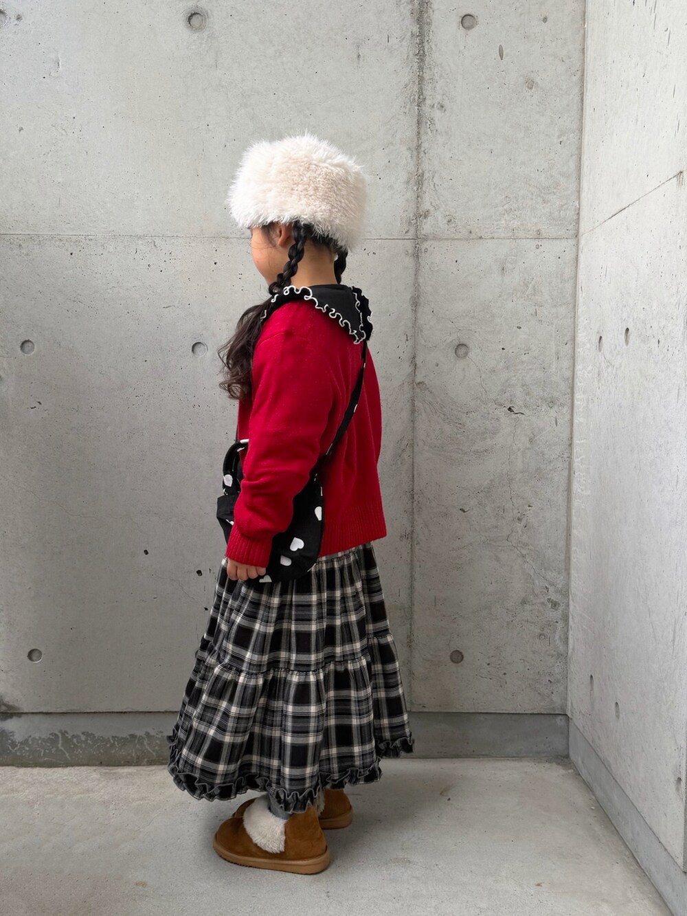 ブラック系のスウェット、ブラウン系のスカート、ブラック系のショルダーバッグを着用したキッズの冬コーディネートの4枚目の写真