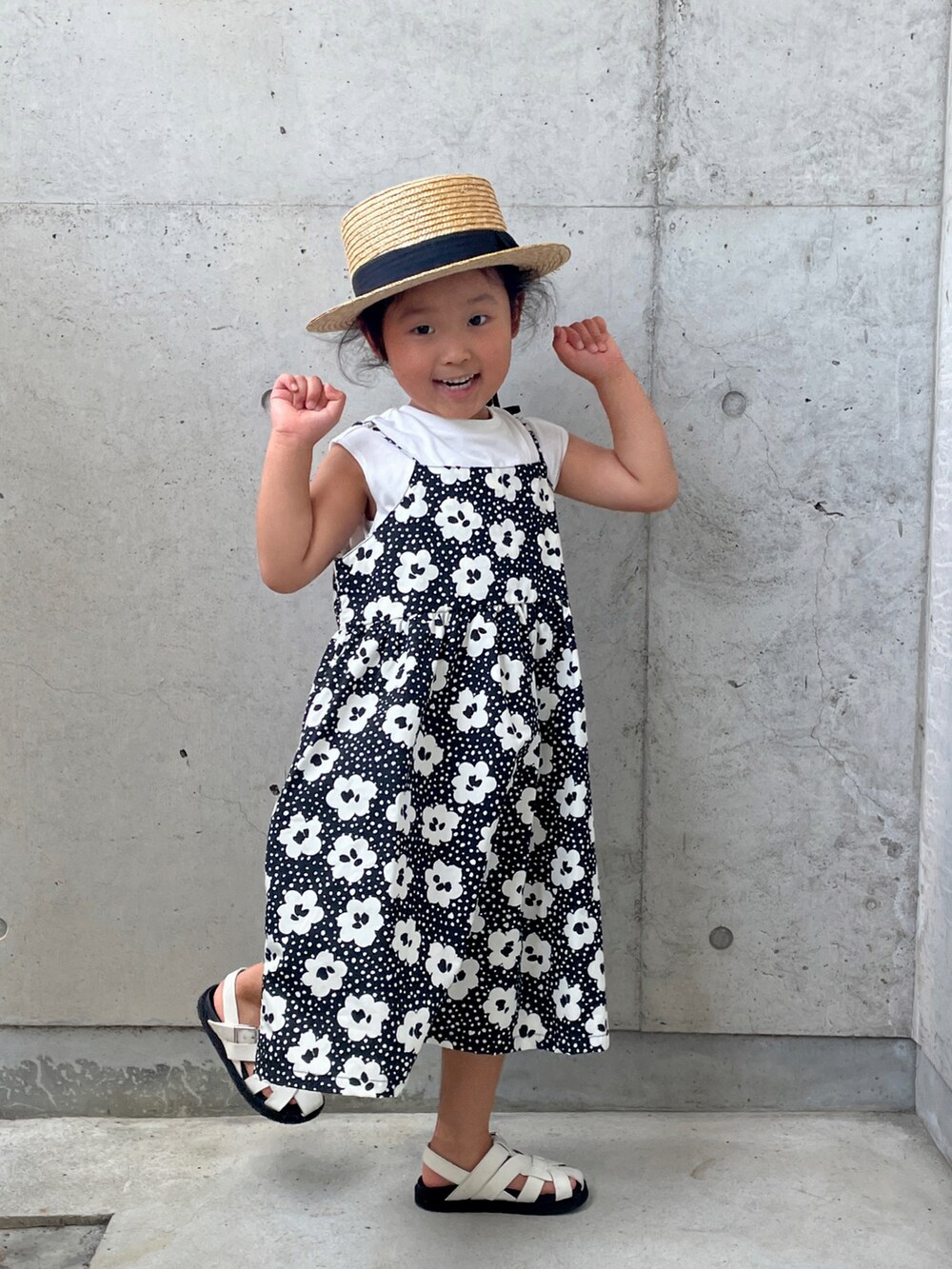 ブラック系のワンピース、ホワイト系のサンダル、ベージュ系のハットを着用したキッズの夏コーディネートの5枚目の写真