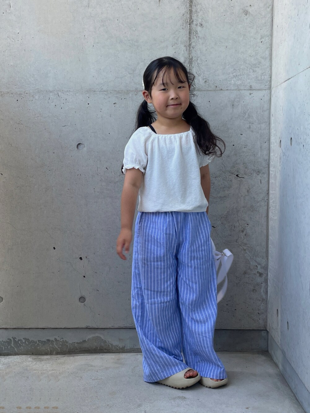 ベージュ系のサンダル、ブラック系のキャミソール、ホワイト系のトップスを着用したキッズの夏コーディネートの4枚目の写真