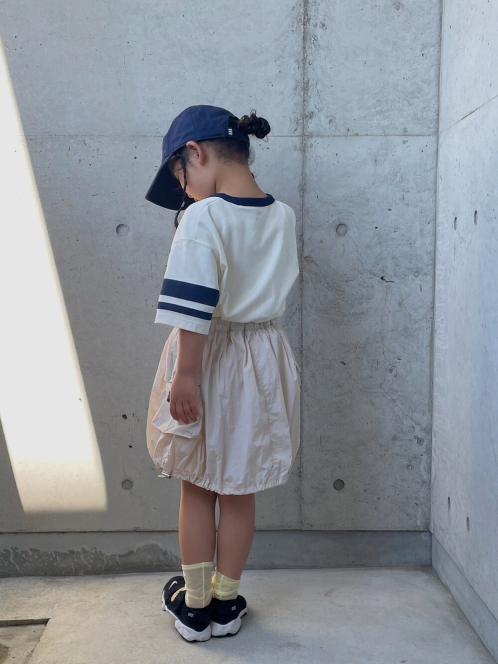 グリーン系のTシャツ/カットソー、ホワイト系のスカート、ブラック系のスニーカーを着用したキッズの夏コーディネートの3枚目の写真