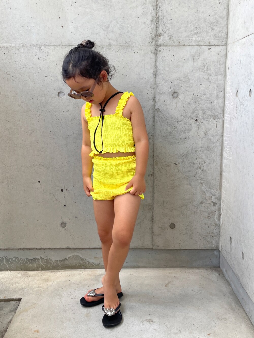 ブラック系のサンダル、イエロー系の水着、ブラック系のハットを着用したキッズの夏コーディネートの2枚目の写真