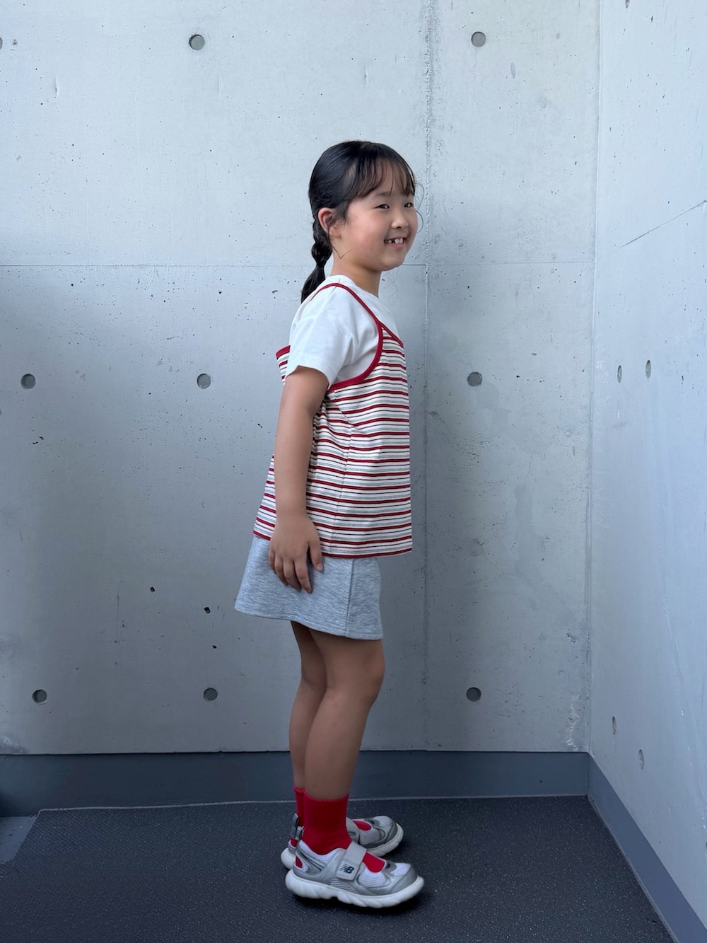 ホワイト系のTシャツ/カットソー、シルバー系のスニーカー、グレー系のスカートを着用したキッズの秋コーディネートの2枚目の写真