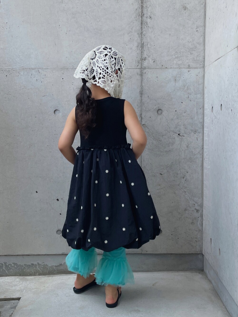 シルバー系のハンドバッグ、ブラック系のワンピース、ブラック系のサンダルを着用したキッズの夏コーディネートの3枚目の写真