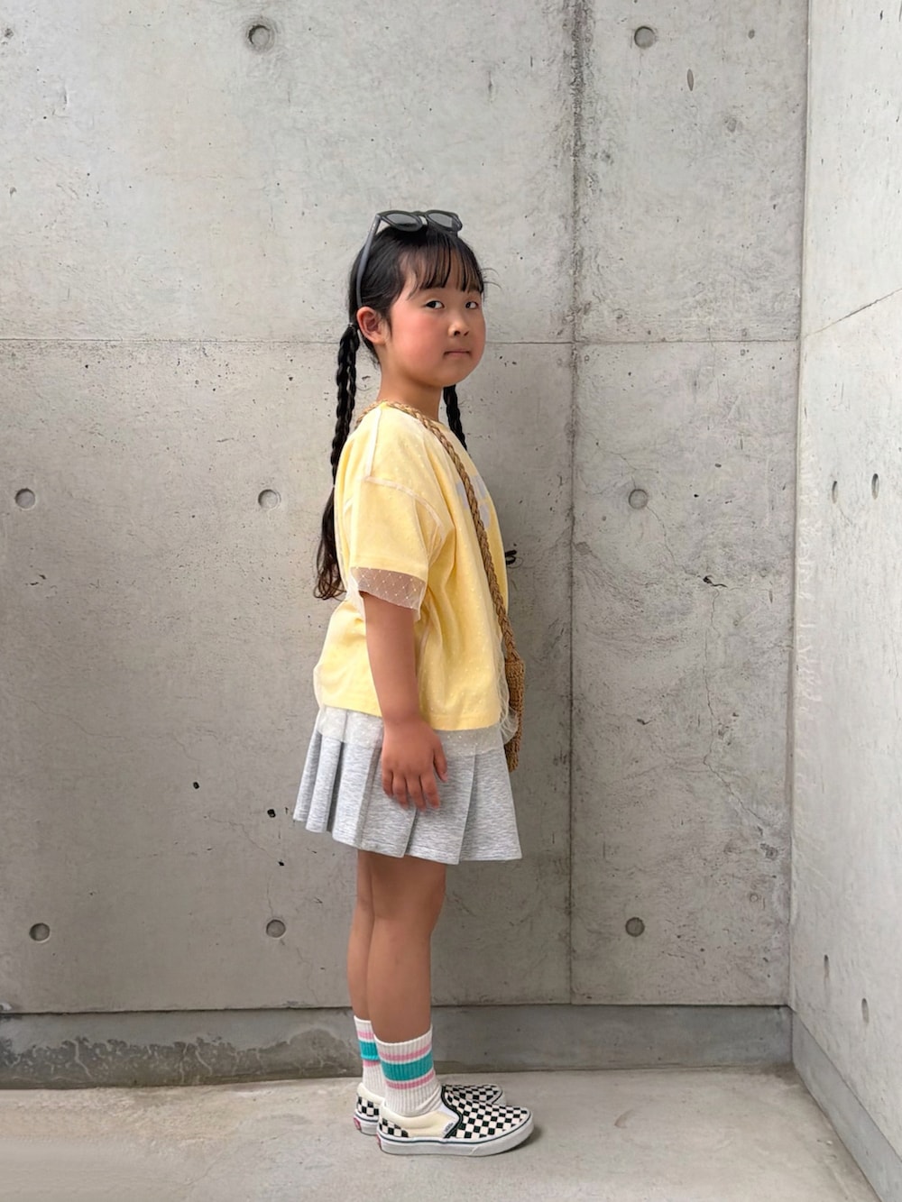 イエロー系のTシャツ/カットソー、ブラック系のスリッポン、グレー系のスカートを着用したキッズの春コーディネートの2枚目の写真