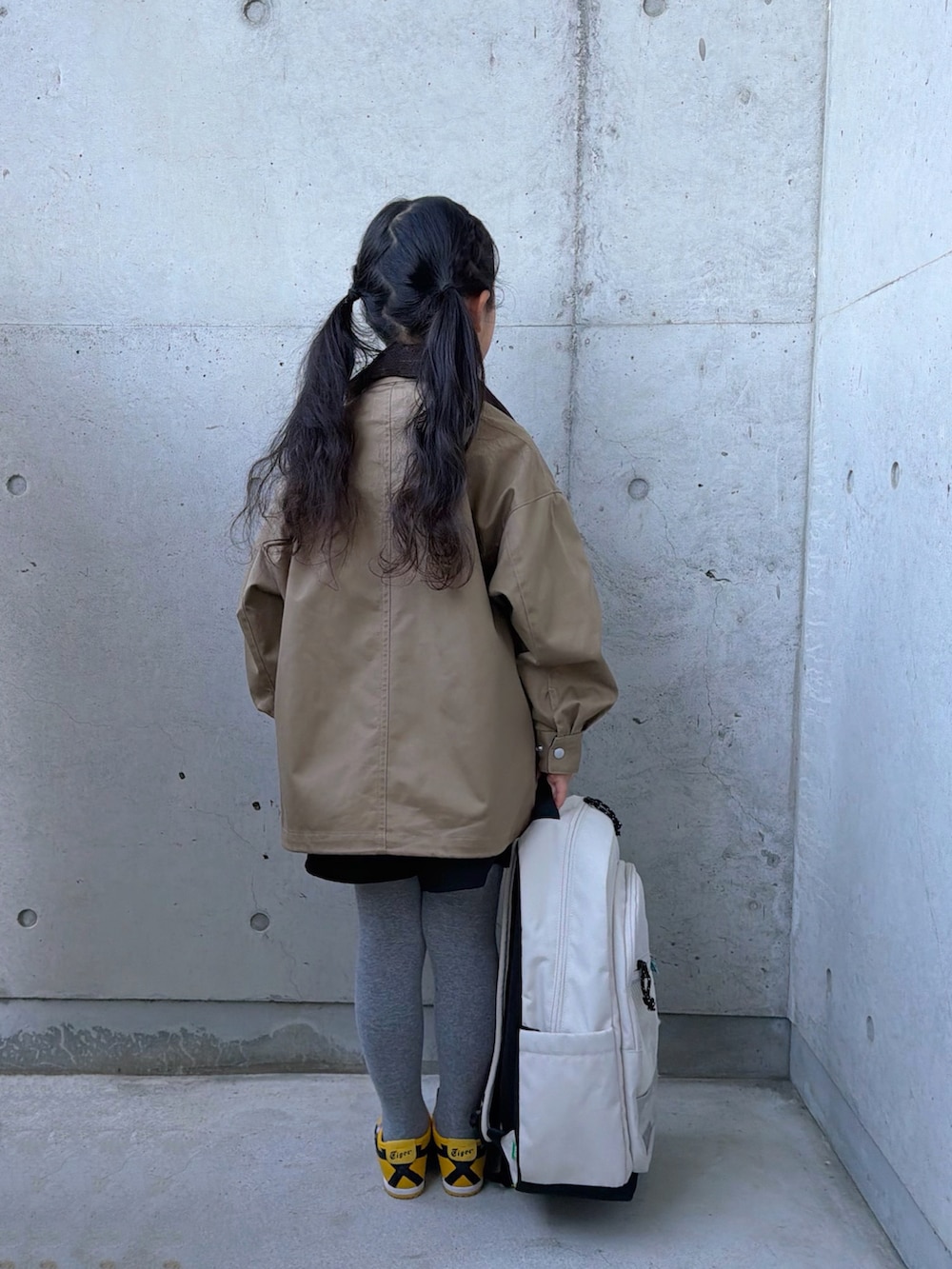 グリーン系のポロシャツ、ベージュ系のミリタリージャケット、イエロー系のスニーカーを着用したキッズの冬コーディネートの2枚目の写真