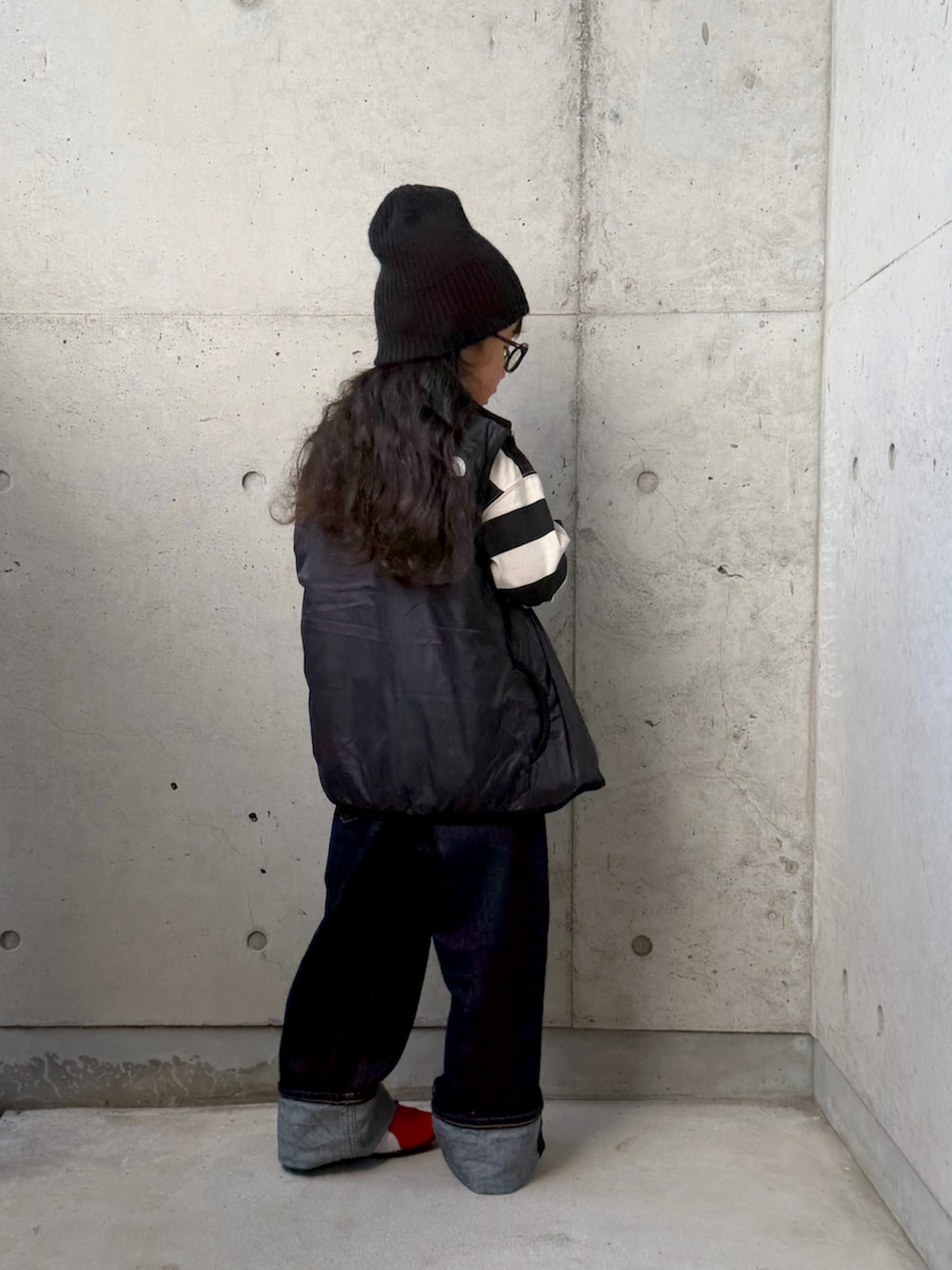 レッド系のスニーカー、ブラック系のベスト、ホワイト系のポロシャツを着用したキッズの秋コーディネートの3枚目の写真