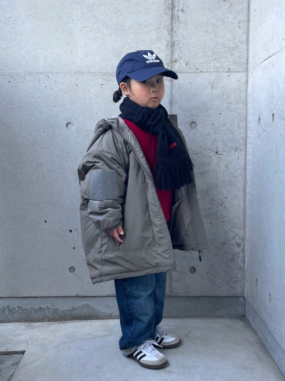 レッド系のニット/セーター、ブルー系のデニムパンツ、グリーン系のブルゾンを着用したキッズの冬コーディネートの5枚目の写真