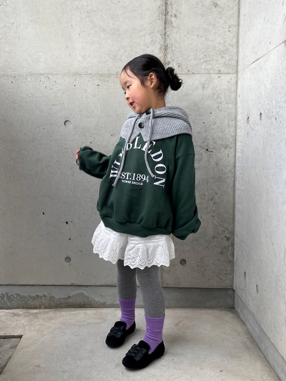 グリーン系のトップス、ホワイト系のパンツ、ブラック系のその他シューズを着用したキッズの冬コーディネートの2枚目の写真