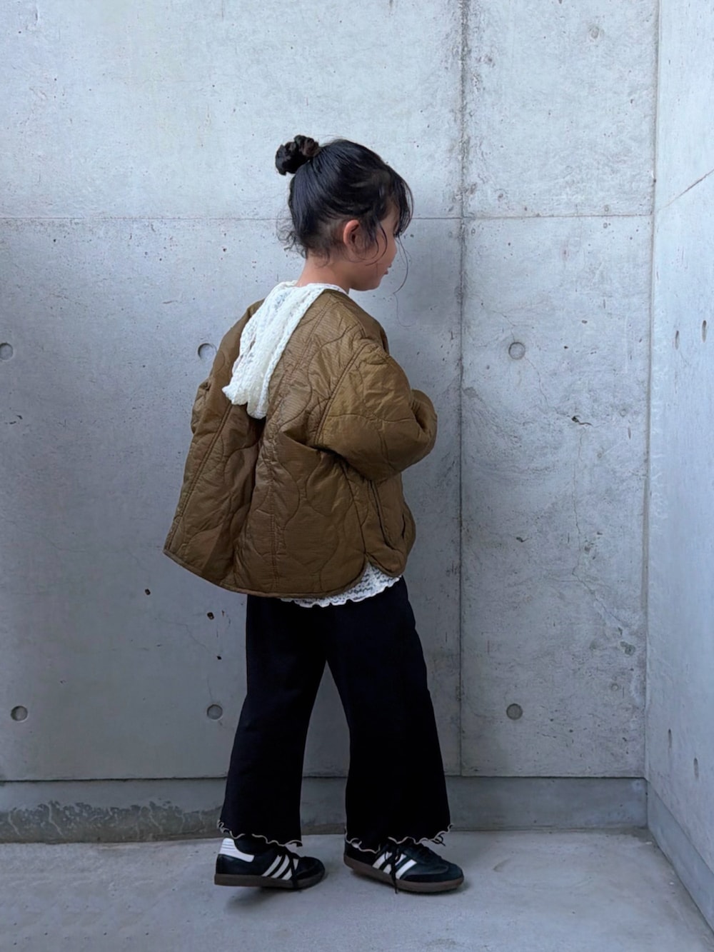 ブラウン系のダウンジャケット/コート、ブラック系のスニーカー、ホワイト系のTシャツ/カットソーを着用したキッズの秋コーディネートの5枚目の写真