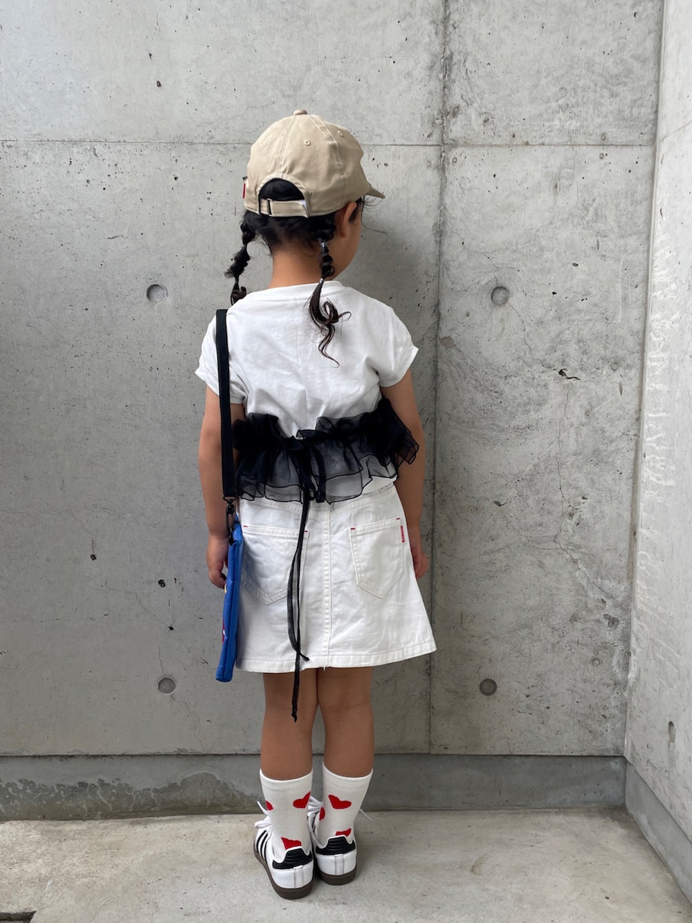 ホワイト系のスカート、ホワイト系のTシャツ/カットソー、ホワイト系のスニーカーを着用したキッズの春コーディネートの3枚目の写真