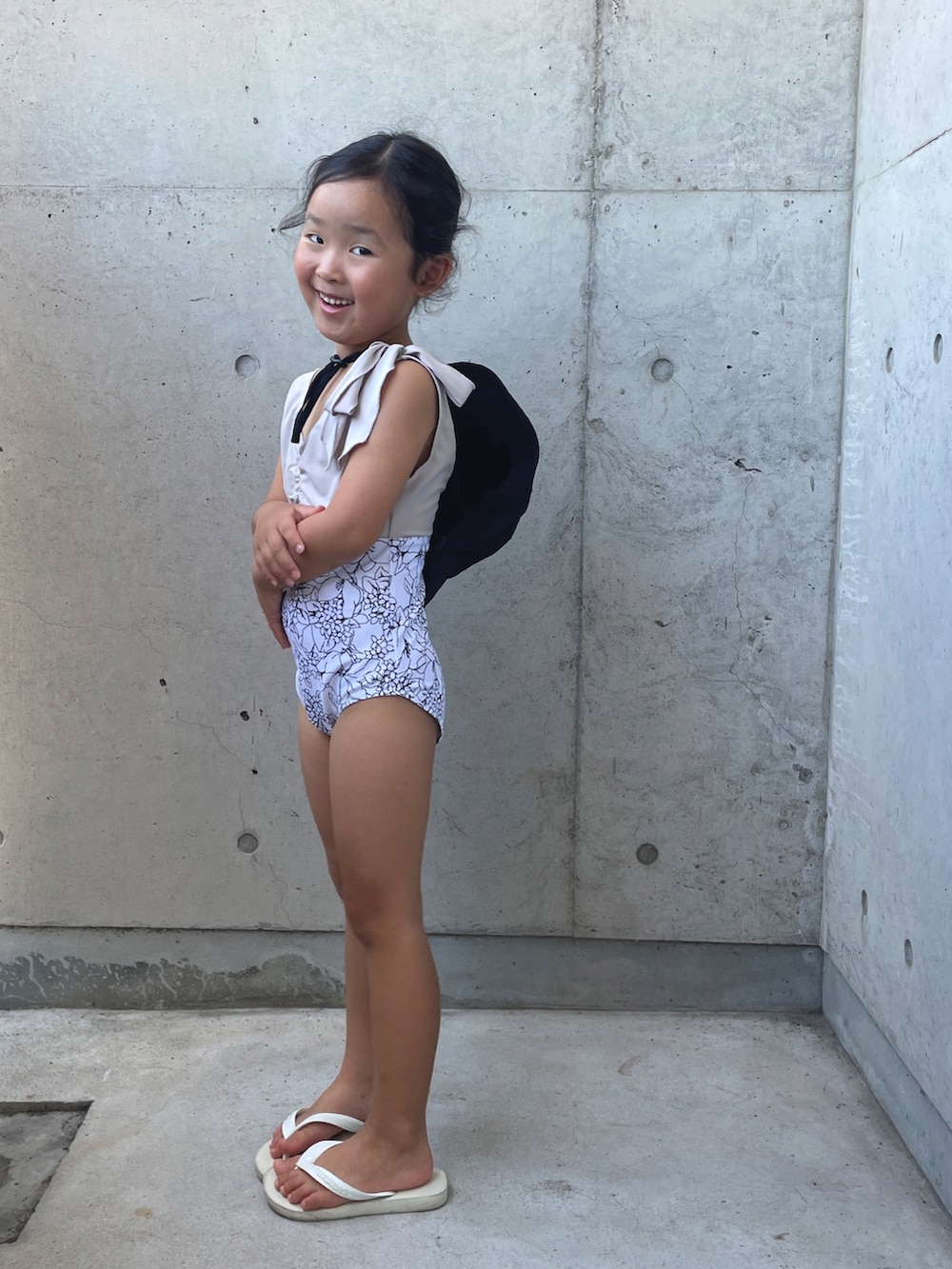 ホワイト系のサンダル、ブラック系のハット、ホワイト系の水着を着用したキッズの夏コーディネートの3枚目の写真