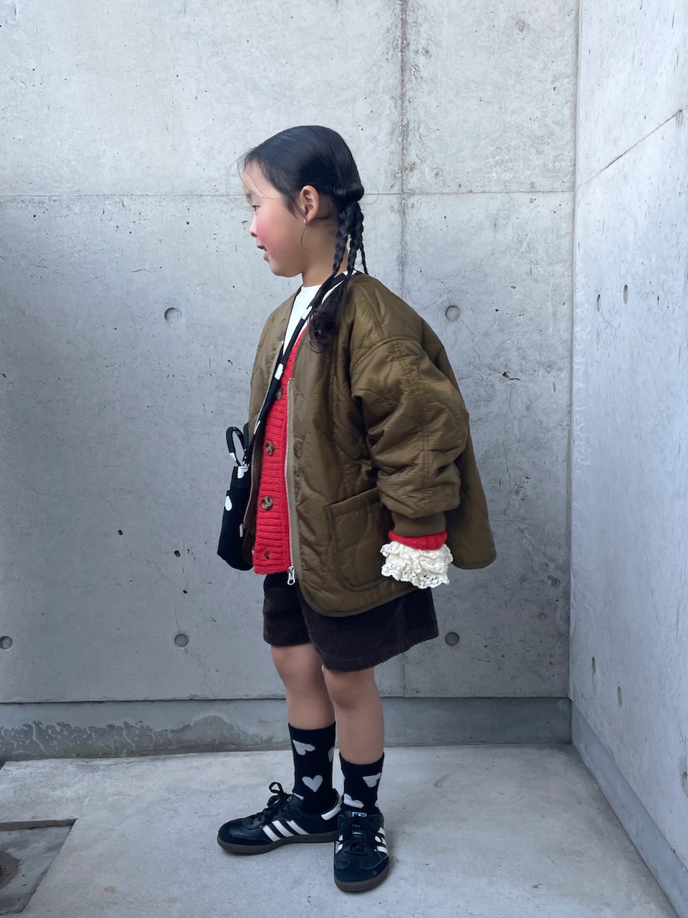 ブラウン系のその他パンツ、ブラック系のショルダーバッグ、オレンジ系のカーディガン/ボレロを着用したキッズの冬コーディネートの5枚目の写真