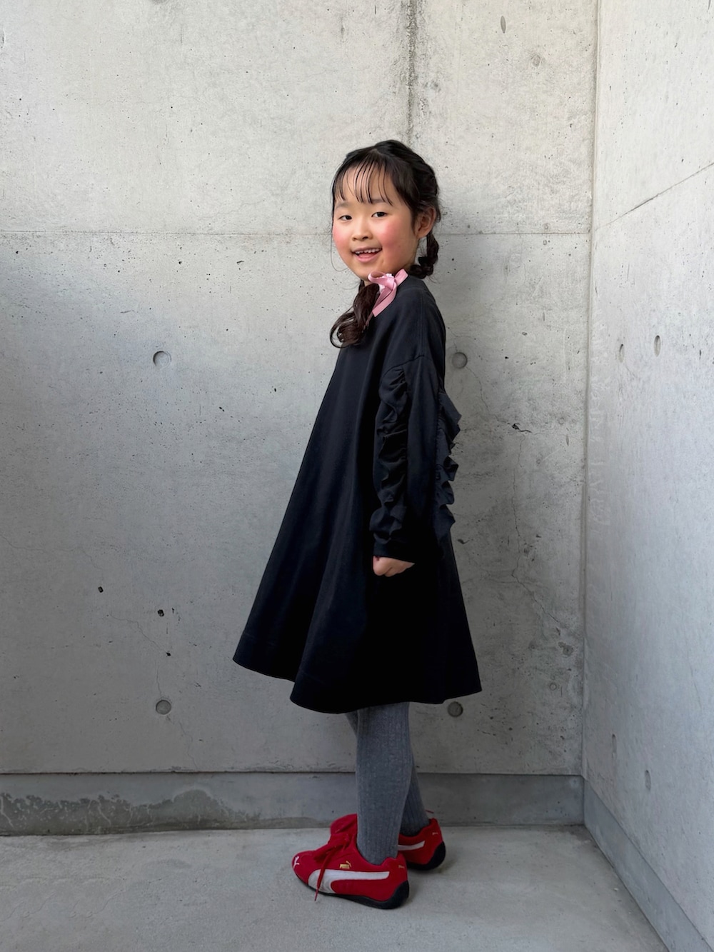 ブラック系のワンピース、レッド系のスニーカー、ピンク系のトートバッグを着用したキッズの春コーディネートの5枚目の写真