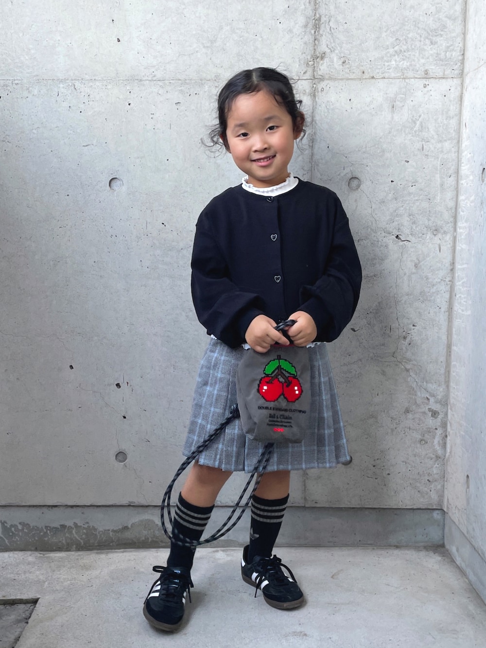 レッド系のパンツ、ブラック系のカーディガン/ボレロ、グレー系のショルダーバッグを着用したキッズの秋コーディネートの5枚目の写真