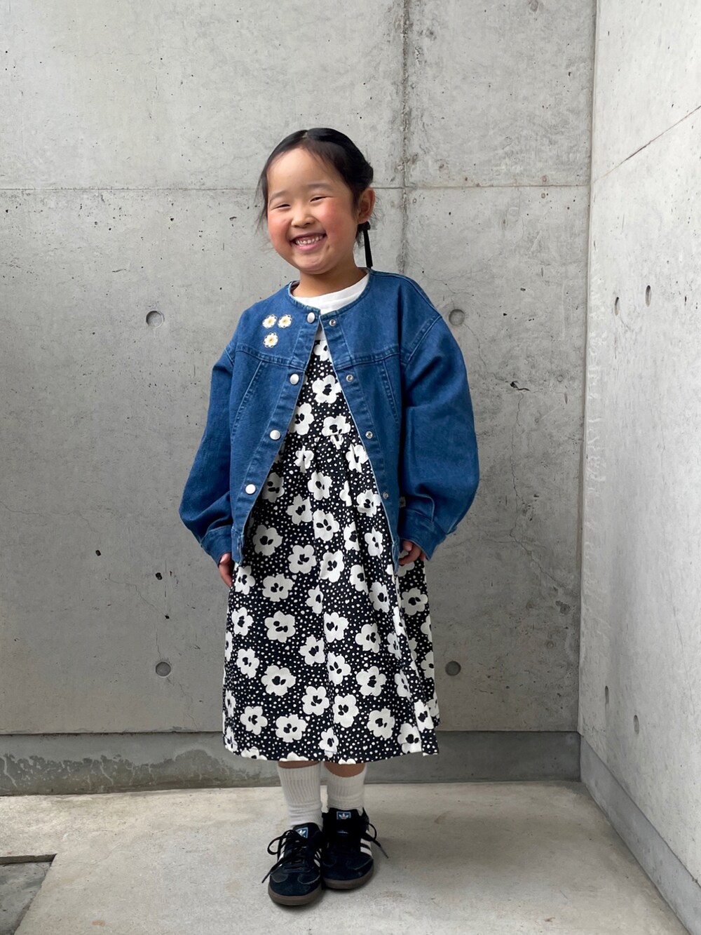 ブラック系のスニーカー、ブラック系のワンピース、ブルー系のデニムジャケットを着用したキッズの春コーディネートの3枚目の写真