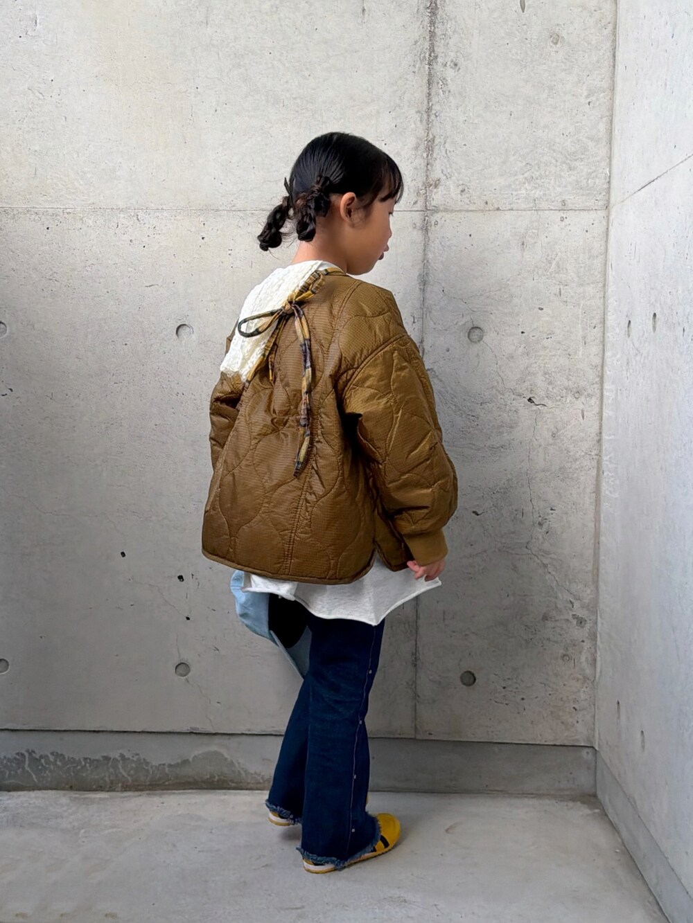 ブルー系のデニムパンツ、グレー系のワンピース、イエロー系のバックパック/リュックを着用したキッズの秋コーディネートの2枚目の写真