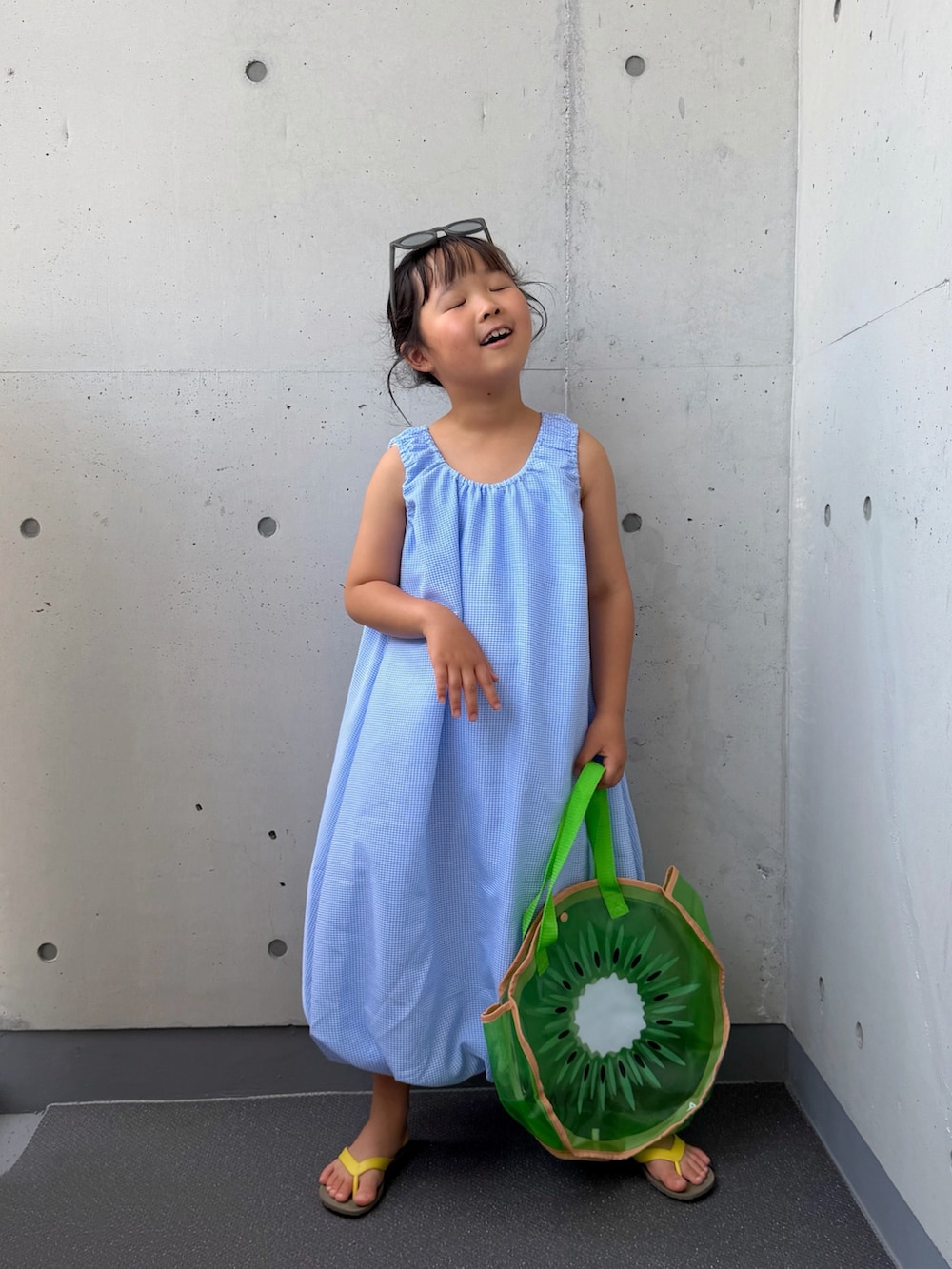 ブルー系のワンピース、グリーン系のトートバッグ、ブラウン系のサンダルを着用したキッズの夏コーディネートの5枚目の写真