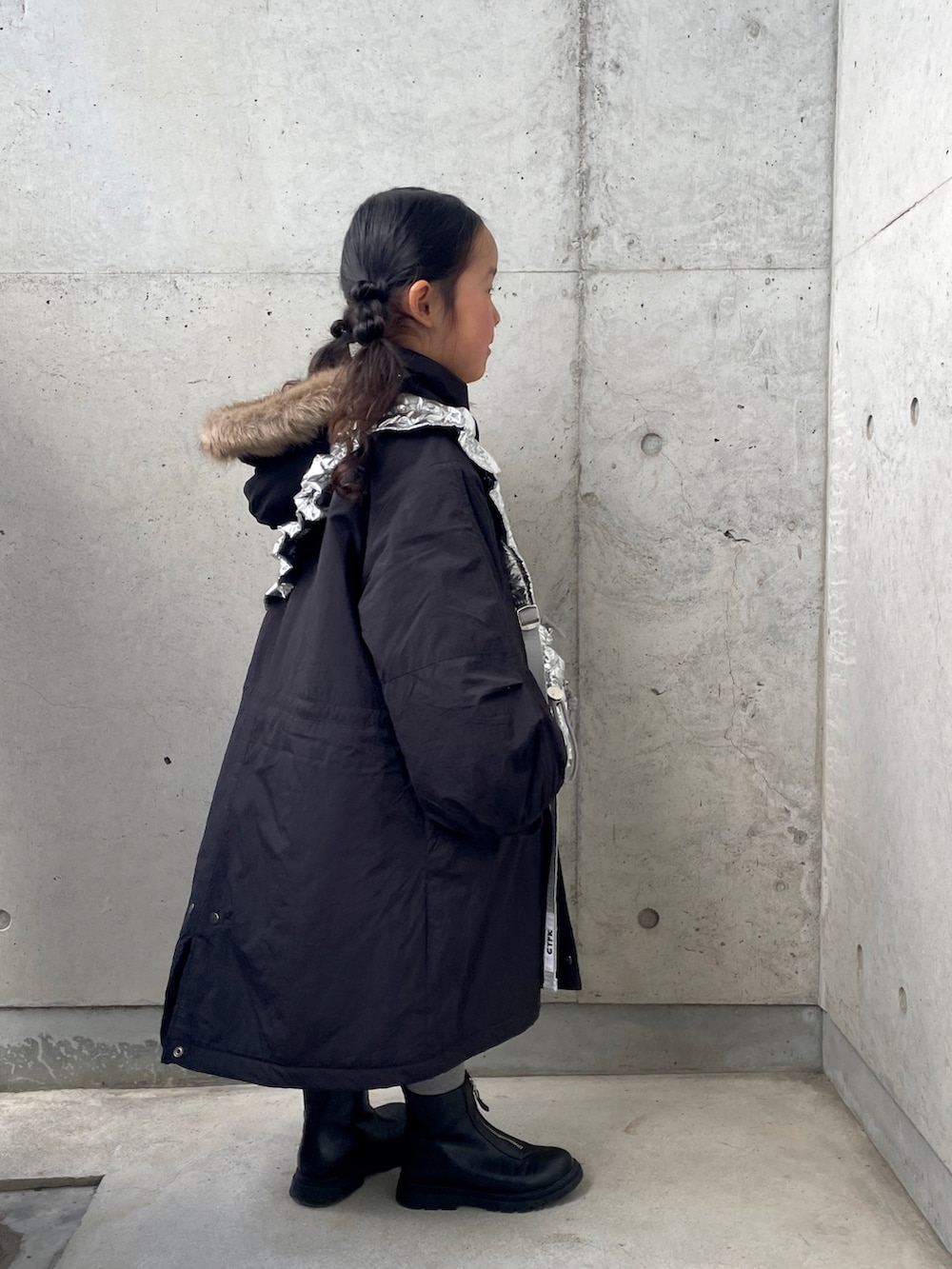 シルバー系のショルダーバッグ、ブラック系のミリタリージャケット、ブラック系のブーツを着用したキッズの冬コーディネートの2枚目の写真