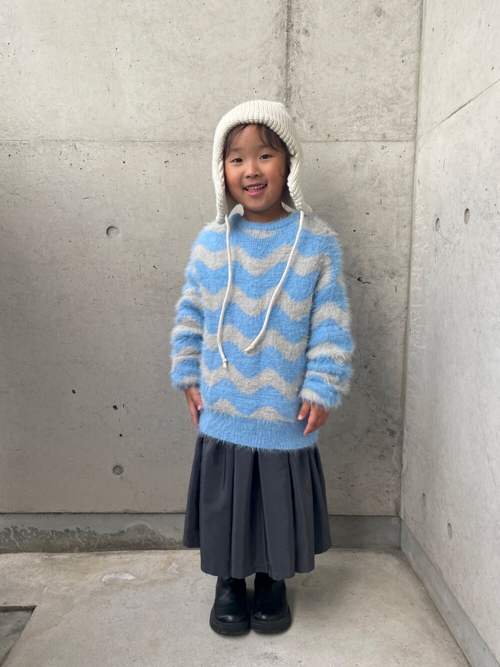 ブルー系のニット/セーター、グレー系のワンピース、シルバー系のトートバッグを着用したキッズの秋コーディネートの5枚目の写真