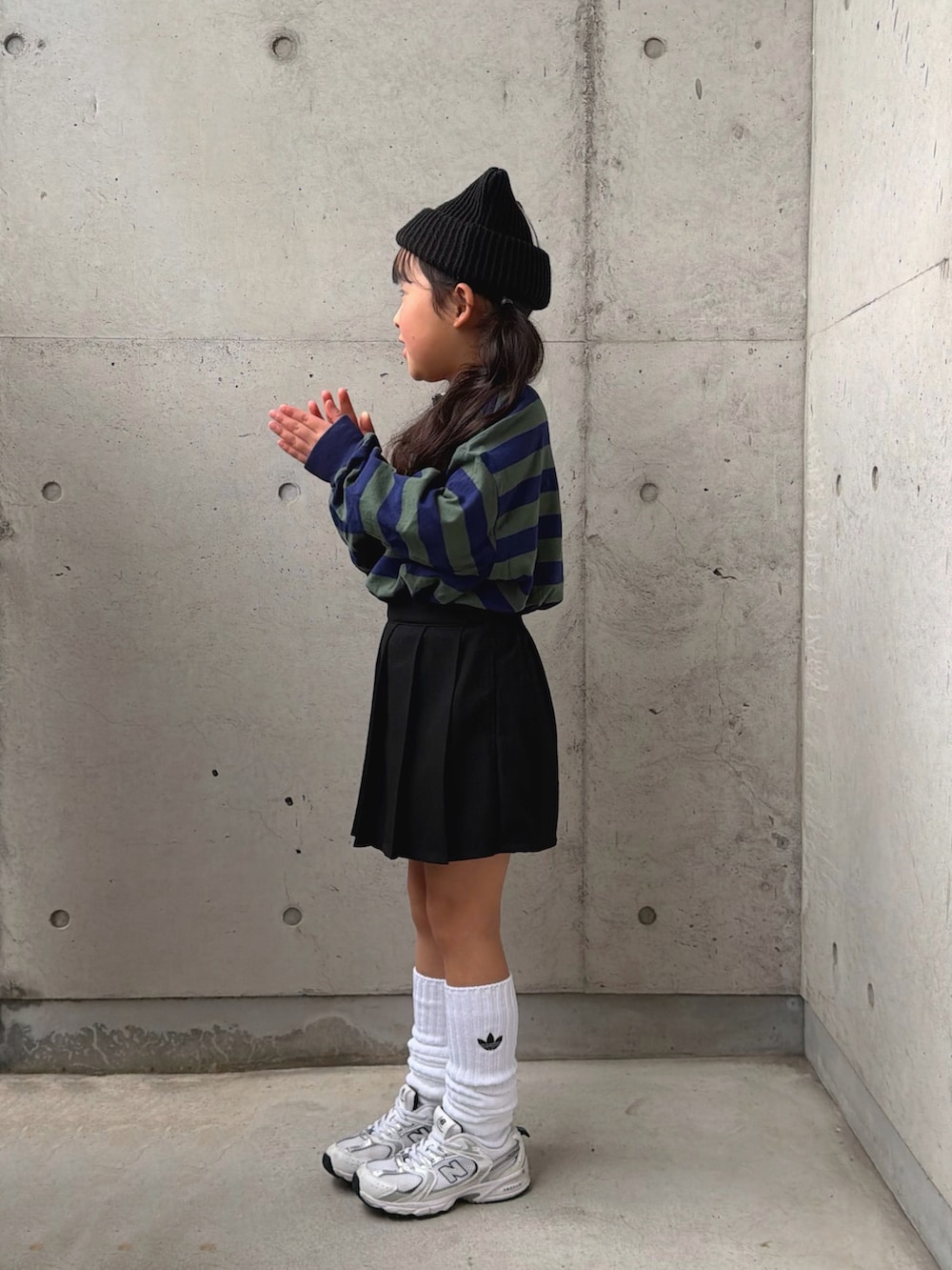 グリーン系のポロシャツ、ホワイト系のスニーカー、ブラック系のパンツを着用したキッズの冬コーディネートの2枚目の写真