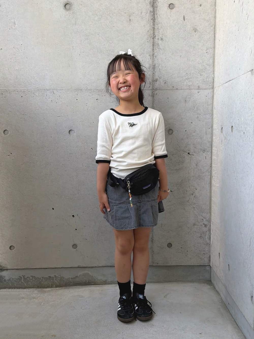 ブラック系のボディバッグ/ウエストポーチ、ホワイト系のTシャツ/カットソー、グレー系のスカートを着用したキッズの春コーディネートの2枚目の写真