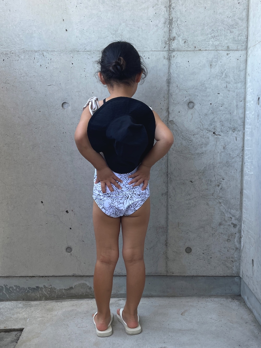 ホワイト系のサンダル、ブラック系のハット、ホワイト系の水着を着用したキッズの夏コーディネートの2枚目の写真