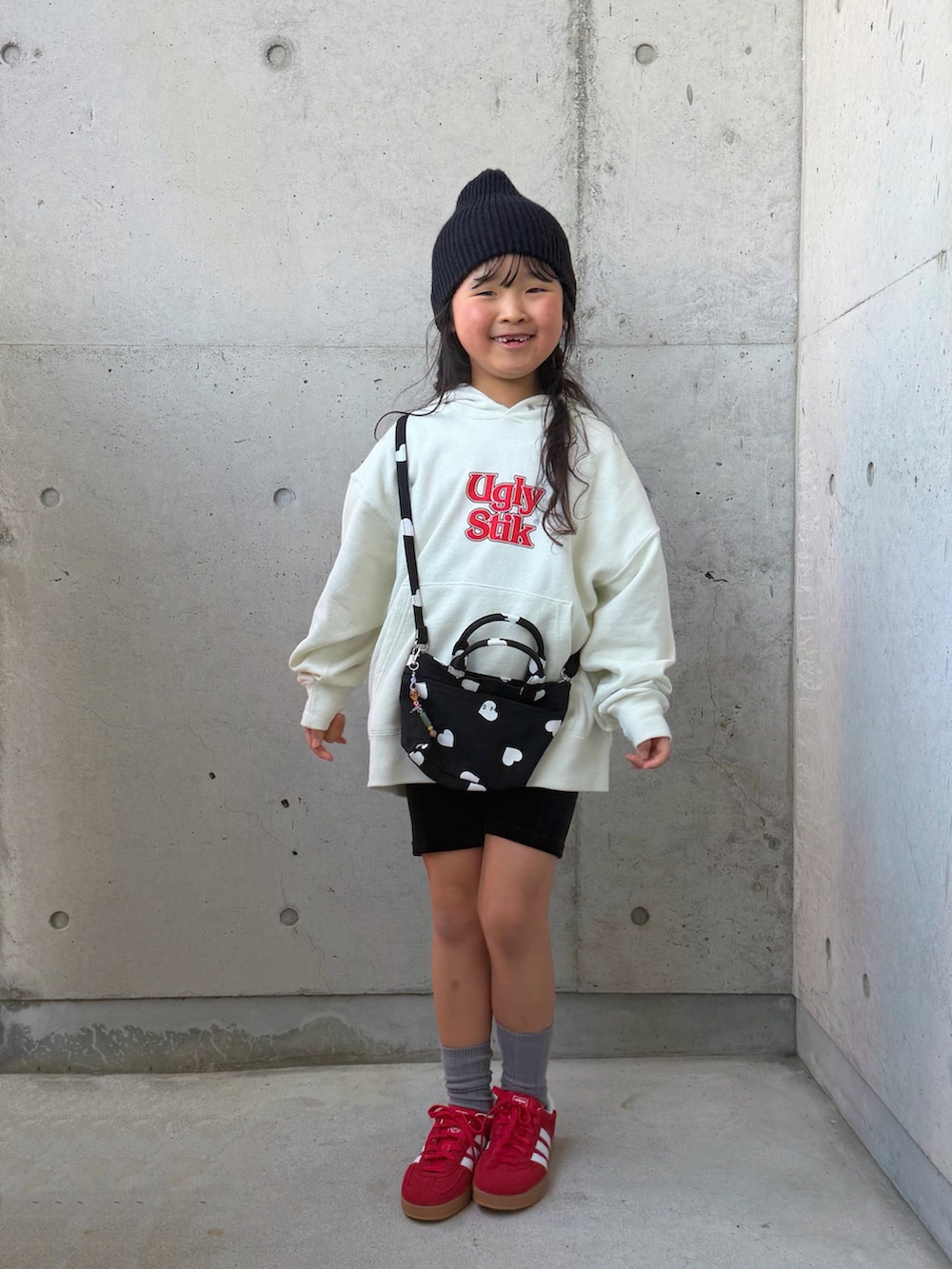 ホワイト系のパーカー、ブラック系のショルダーバッグ、レッド系のスニーカーを着用したキッズの冬コーディネートの5枚目の写真