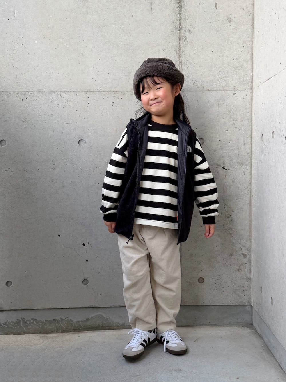 ホワイト系のスニーカー、ベージュ系のその他パンツ、ブラック系のベストを着用したキッズの秋コーディネートの4枚目の写真