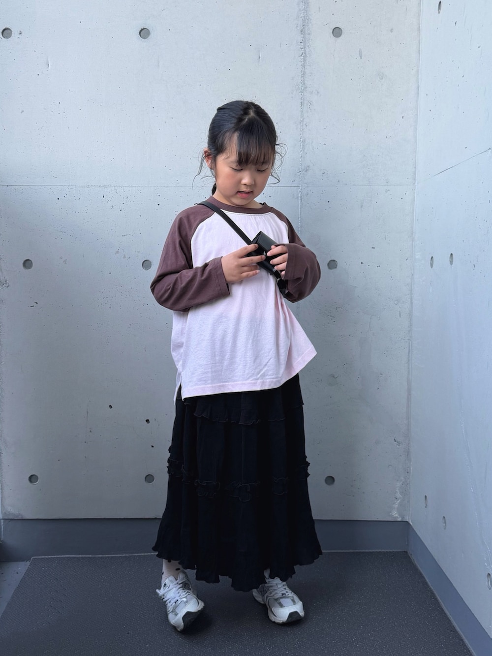 ホワイト系のスニーカー、ピンク系のTシャツ/カットソー、ブラック系のスカートを着用したキッズの秋コーディネートの2枚目の写真