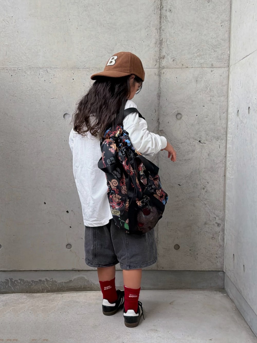 ブラック系のスニーカー、ホワイト系のTシャツ/カットソー、ブラック系のデニムパンツを着用したキッズの秋コーディネートの5枚目の写真