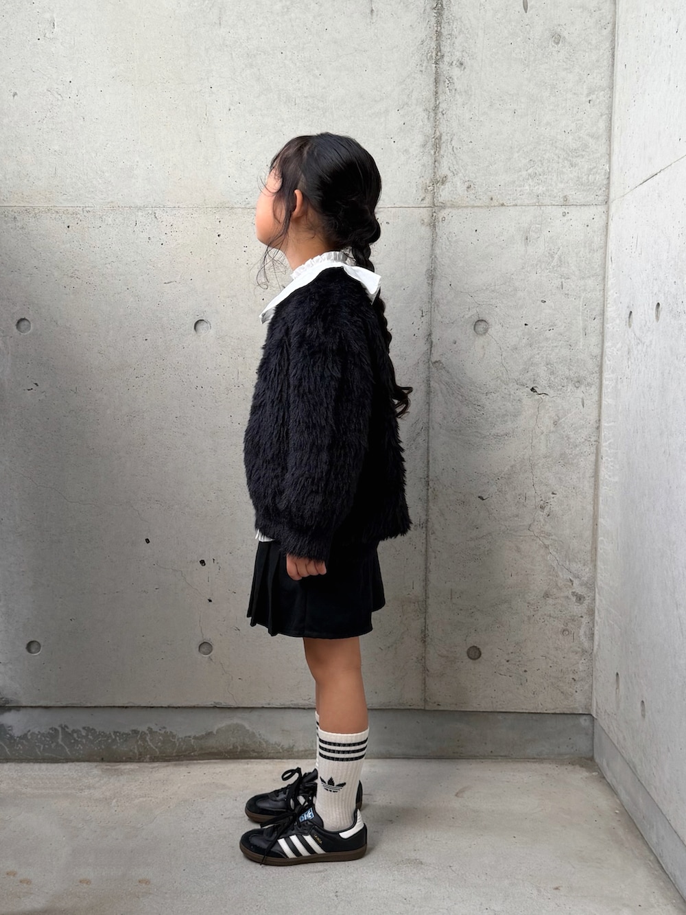 ブラック系のニット/セーター、ブラック系のスニーカー、ホワイト系のシャツ/ブラウスを着用したキッズの秋コーディネートの2枚目の写真