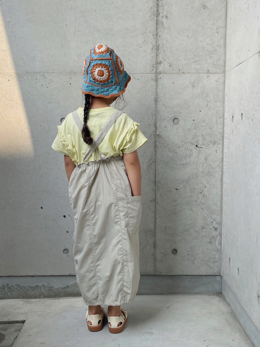 ベージュ系のTシャツ/カットソー、ベージュ系のワンピース、ホワイト系のサンダルを着用したキッズの夏コーディネートの4枚目の写真