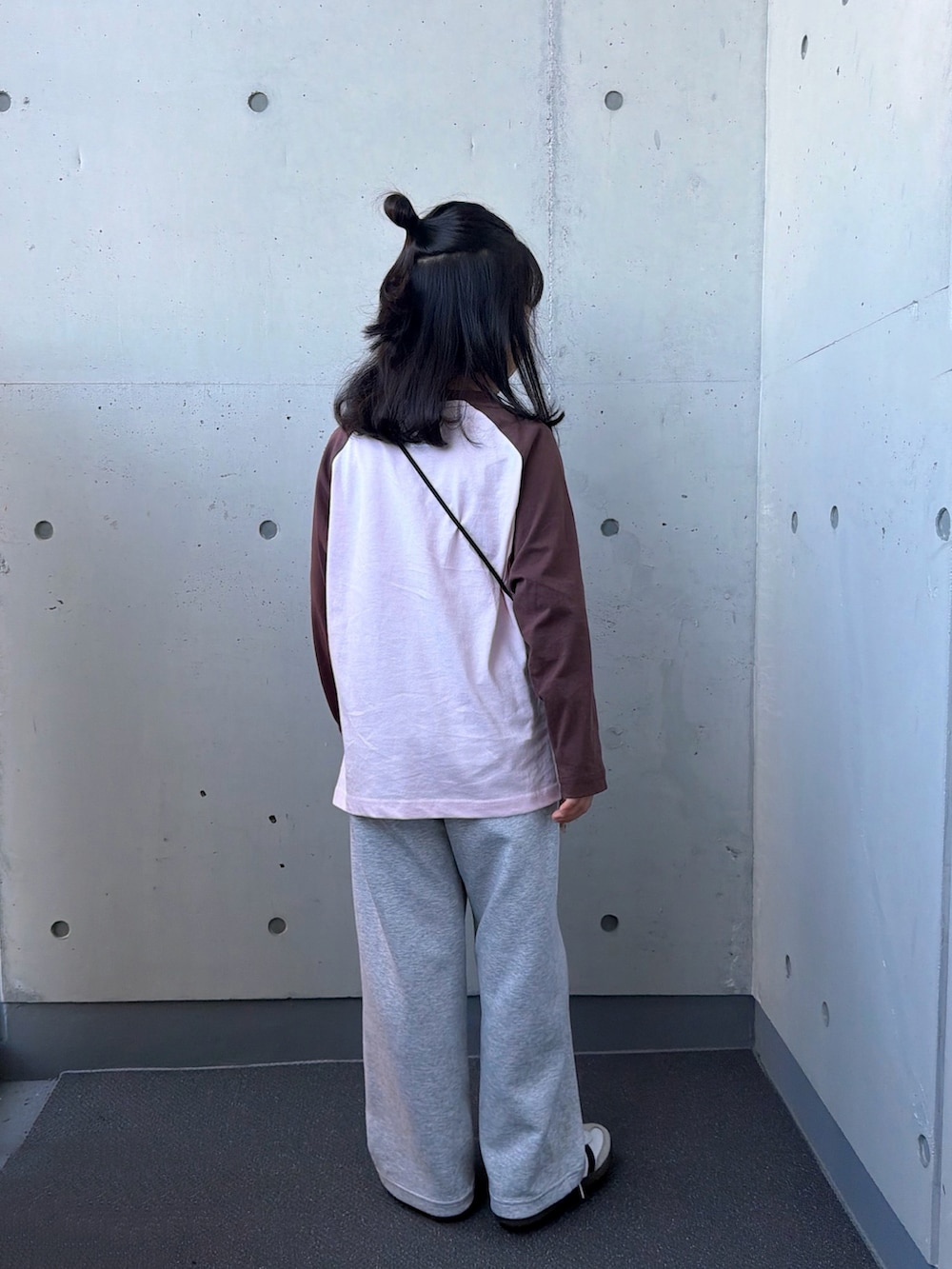 ピンク系のTシャツ/カットソー、ブラウン系のショルダーバッグ、ホワイト系のスニーカーを着用したキッズの秋コーディネートの4枚目の写真