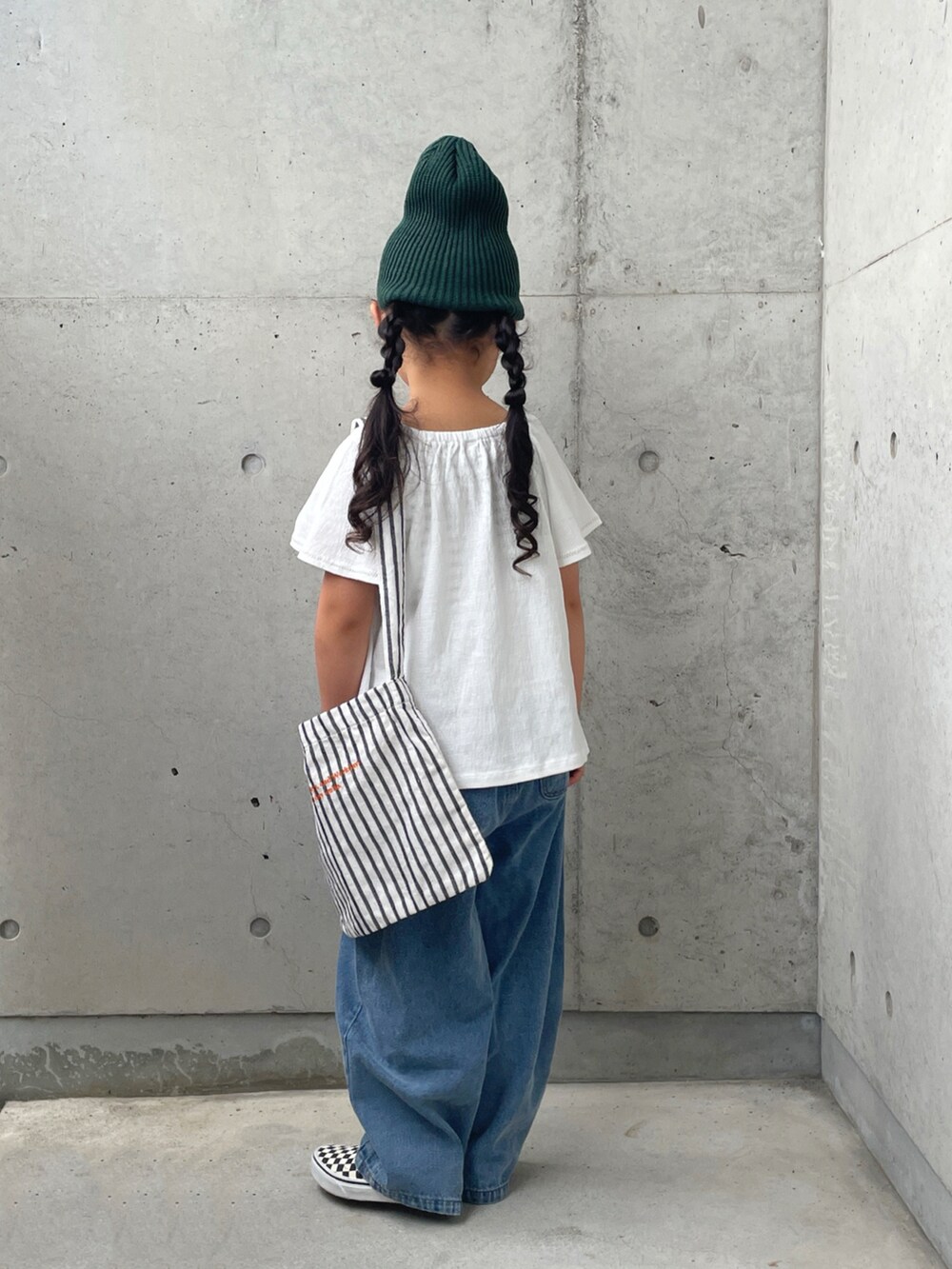 ホワイト系のキャミソール、ブラック系のスリッポン、ホワイト系のトップスを着用したキッズの秋コーディネートの3枚目の写真