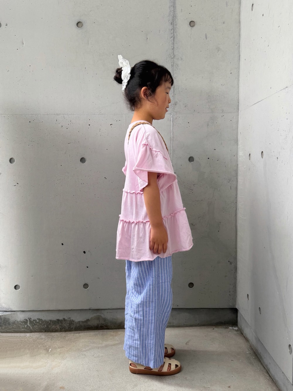 ピンク系のTシャツ/カットソー、ベージュ系のショルダーバッグ、ホワイト系のサンダルを着用したキッズの夏コーディネートの2枚目の写真