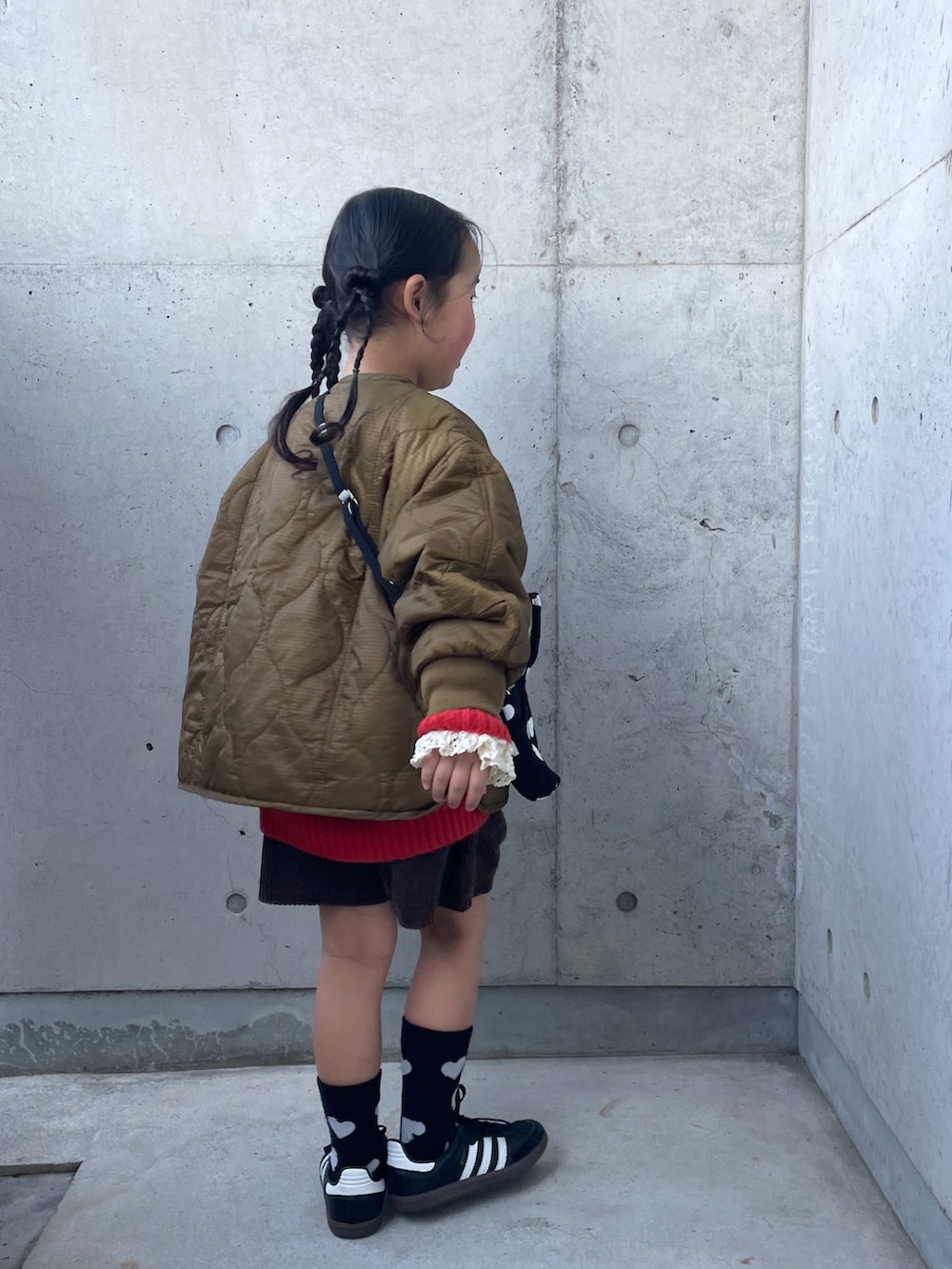 ブラウン系のその他パンツ、ブラック系のショルダーバッグ、オレンジ系のカーディガン/ボレロを着用したキッズの冬コーディネートの2枚目の写真