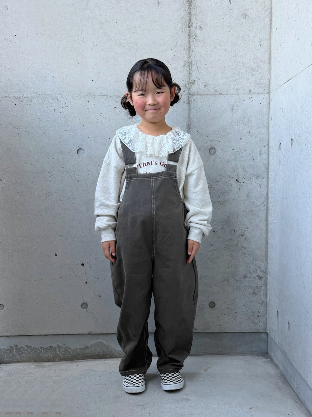 グレー系のサロペット/オーバーオール、ベージュ系のスウェット、ブラック系のスリッポンを着用したキッズの秋コーディネートの3枚目の写真