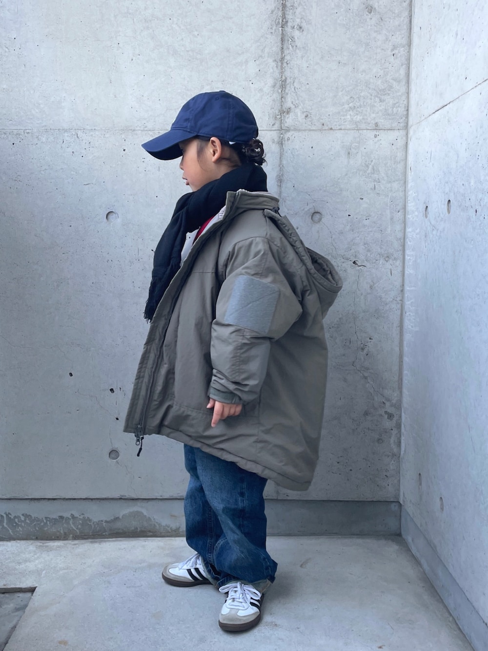 レッド系のニット/セーター、ブルー系のデニムパンツ、グリーン系のブルゾンを着用したキッズの冬コーディネートの2枚目の写真