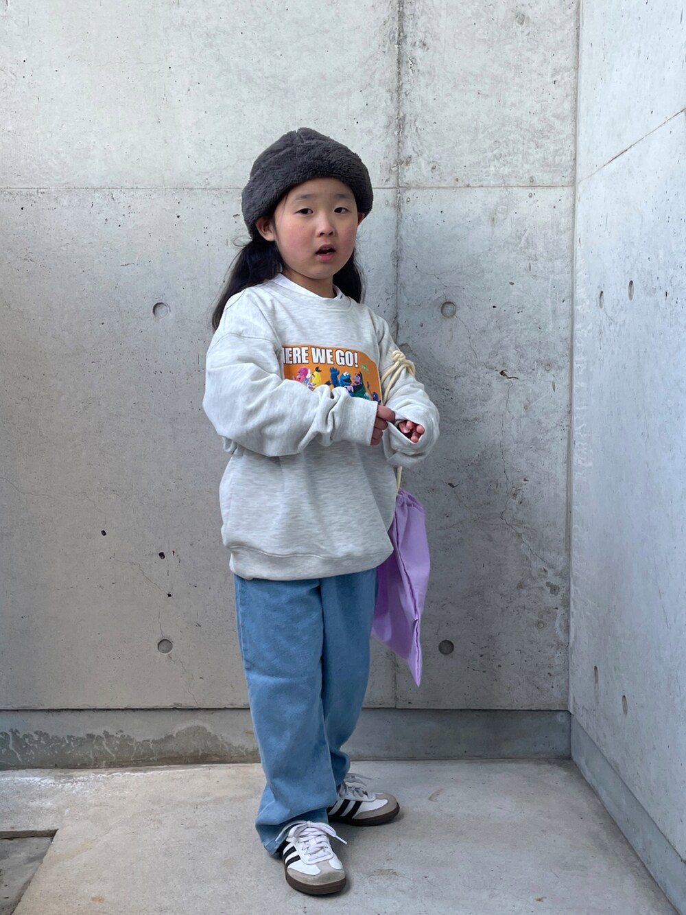 パープル系のエコバッグ/サブバッグ、グレー系のスウェット、ブルー系のデニムパンツを着用したキッズの冬コーディネートの4枚目の写真