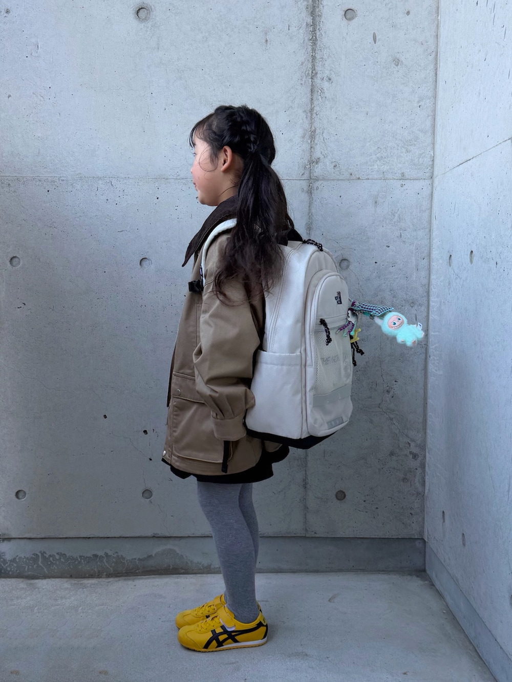 グリーン系のポロシャツ、ベージュ系のミリタリージャケット、イエロー系のスニーカーを着用したキッズの冬コーディネートの3枚目の写真