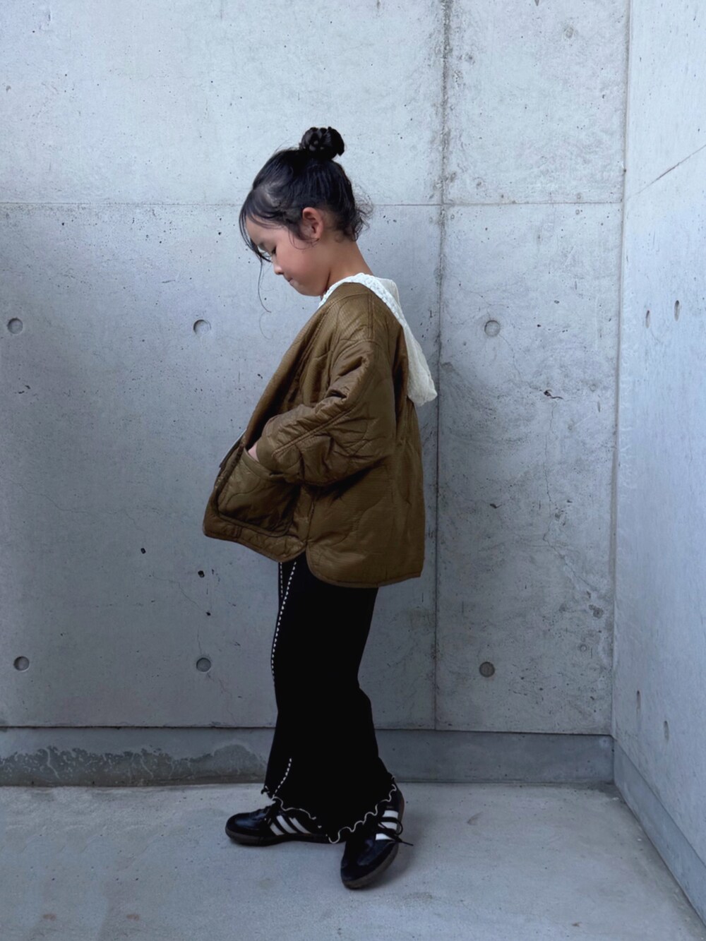 ブラウン系のダウンジャケット/コート、ブラック系のスニーカー、ホワイト系のTシャツ/カットソーを着用したキッズの秋コーディネートの2枚目の写真