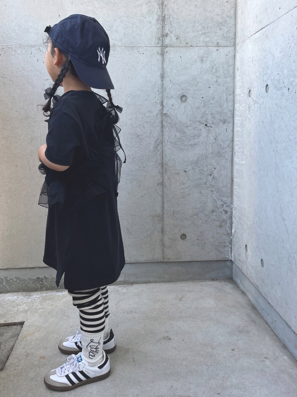 ブラック系のワンピース、ホワイト系のスニーカー、ブラック系のバレッタ/ヘアクリップを着用したキッズの春コーディネートの2枚目の写真