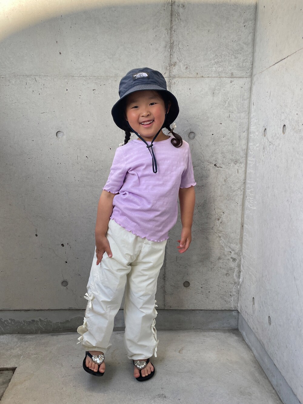 パープル系のTシャツ/カットソー、ホワイト系のその他パンツ、ブラック系のサンダルを着用したキッズの春コーディネートの3枚目の写真