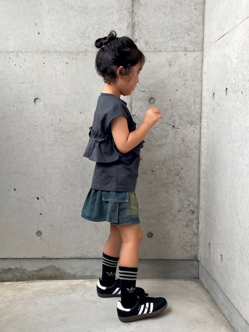 グレー系のタンクトップ、ブルー系のスカート、ブラック系のスニーカーを着用したキッズの夏コーディネートの2枚目の写真