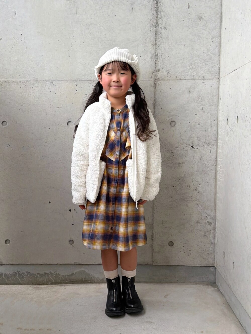 ブラック系のブーツ、ホワイト系のジャケット/アウター、イエロー系のワンピースを着用したキッズの秋コーディネートの5枚目の写真