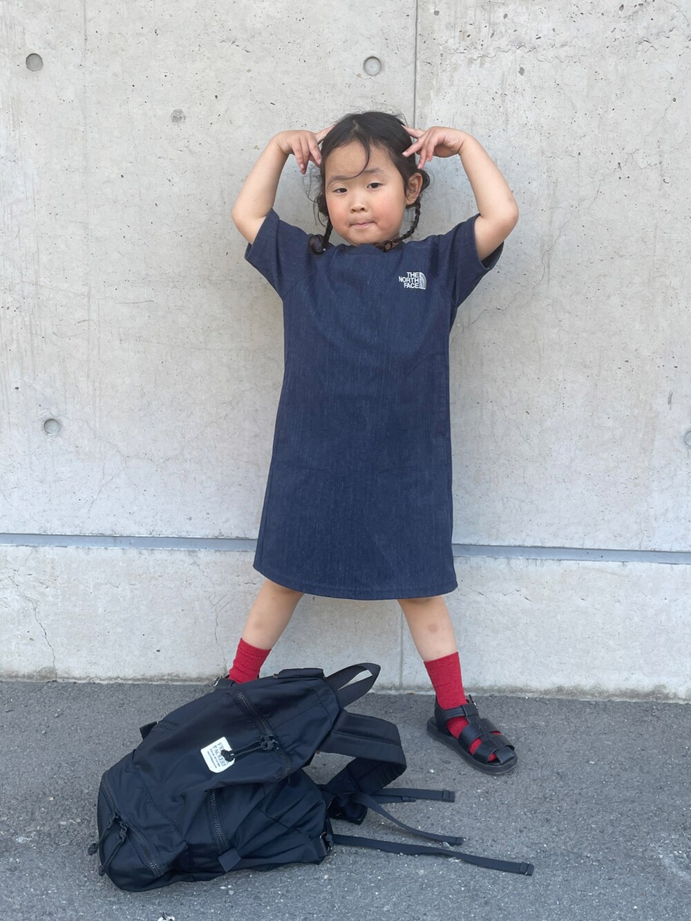 ブラック系のサンダル、ブラック系のバックパック/リュック、ブルー系のワンピースを着用したキッズの春コーディネートの2枚目の写真