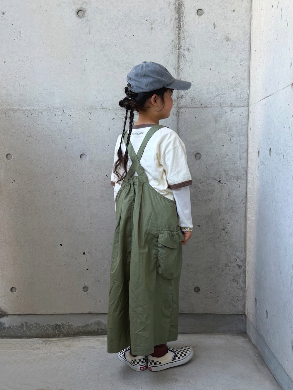 ブラック系のスリッポン、グリーン系のジャンパースカート、ホワイト系のTシャツ/カットソーを着用したキッズの春コーディネートの5枚目の写真